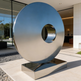 Modern metal sculpture in front of a building
Polished metal disc mounted on a rectangular pedestal