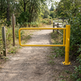 Industrial yellow powder-coated steel P-gate access barrier with mounting plate for parks, parking lots, and pedestrian trails.