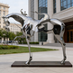 Polished metallic sculpture combining a stylized horse and rider with open geometric sections
