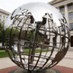Reflective polished metal sculpture of a world globe with detailed geographic outlines
