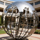 Polished silver‑tone world globe sculpture showing continents on an open grid sphere.
