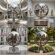 Reflective metal sculpture of Earth featuring a grid sphere and solid continent forms