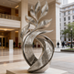 Decorative metal sculpture in a public space with people and buildings in the background