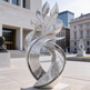 Reflective abstract sculpture with ornate swirling engravings and elegant flame‑inspired curves