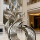 Decorative metal sculpture in the form of a leaf with intricate patterns in an elegant interior setting.