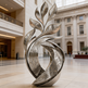 Reflective metallic sculpture featuring upward flowing shapes with detailed engraved motifs