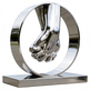 Reflective metal artwork featuring interlocking hands framed by a polished circular ring