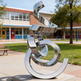 Contemporary polished metal artwork composed of looping, intertwined ribbon‑like forms.