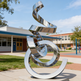 Polished steel‑like abstract sculpture with fluid ribbon curves and mirrored highlights