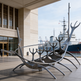 Contemporary abstract metal sculpture with smooth reflective curves evoking a historic ship silhouette