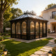 Decorative wrought iron greenhouse with tall arched windows and glass roof
