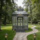 Decorative glass gazebo in a lush garden setting with a stone path leading to it.