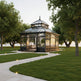 Glass gazebo in a garden setting with trees and a clear sky