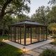 Gazebo with glass walls in a garden setting with trees and lanterns.