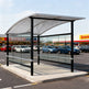 Side profile of modern shopping cart shelter featuring transparent glass panels and black steel supports.