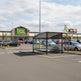 Rear angle of shopping cart shelter with perforated roof and full glass enclosure.