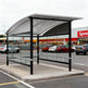 TAIMCO shopping cart shelter installed outdoors with curved metal roof and glass side panels.