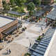 Outdoor shopping area with 'Central Plaza Coffee' and 'Outlet Market' signs, people walking and sitting.
