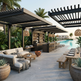 Outdoor patio area with cabana bar, tables, and chairs near a pool.