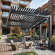 Outdoor patio area with pergola, tables, and chairs in an urban setting.
