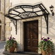 Decorative black metal canopy over a wooden door with potted plants on either side.