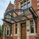 Decorative metal canopy over a wooden door of a large brick building.