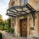 Decorative canopy over a wooden door of a stone building with garden in the background