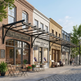 Street view of a row of shops with outdoor seating areas on a sunny day.