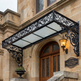 Decorative metal canopy over a door with architectural details on a building facade.