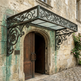 Decorative metal canopy over a stone archway with a wooden door.