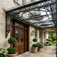 Decorative metal canopy over a door with potted plants and garden view