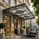 Luxury hotel entrance with classical architecture, car, and people.