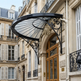 Heritage‑style iron canopy installed above wooden glass‑panel doorway.