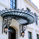 Lantern‑lit glass and iron canopy providing weather protection at building entrance.
