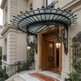 Decorative iron entrance awning featuring curved glass roof and large lantern fixtures.