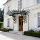 Arched glass canopy with ornate wrought iron scrollwork and dual lantern lights.