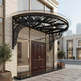 Curved outdoor awning with wrought iron frame and glass roof.