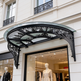 Semi‑circular outdoor glass awning with ornate wrought iron scrollwork.