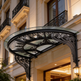Outdoor entrance awning featuring curved glass and ornate ironwork.