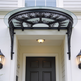 Decorative exterior canopy with curved glass and ornate iron frame.