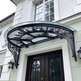 Outdoor wrought iron scrollwork awning with semi‑circular glass top.