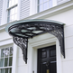 Curved glass entrance canopy featuring decorative wrought iron brackets.