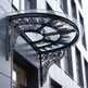 Outdoor wrought iron scrollwork awning with semi‑circular glass top.