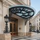 Outdoor entrance awning featuring curved glass and ornate ironwork.