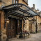 Luxury entrance awning featuring ornate iron scrollwork and glass top panel.