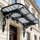 Decorative wrought iron canopy installed above grand building entrance.