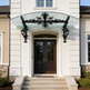 Curved glass canopy mounted above exterior doorway with floral iron detailing.