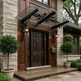 Curved glass canopy mounted above exterior doorway with floral iron detailing.