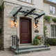 Decorative entrance canopy featuring curved glass roof and ornate iron brackets.