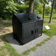 Metal trash bin with two lids in a park setting